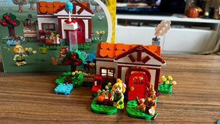 Lego Isabelle's House Visit set, minifigures, and box laid out on a wooden table